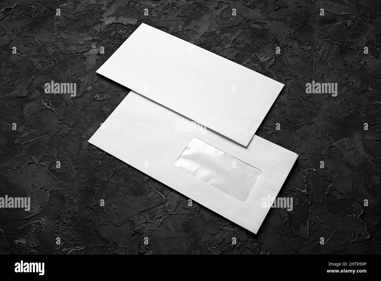 Two blank paper envelopes on black stone background. Back and front. Stock Photo