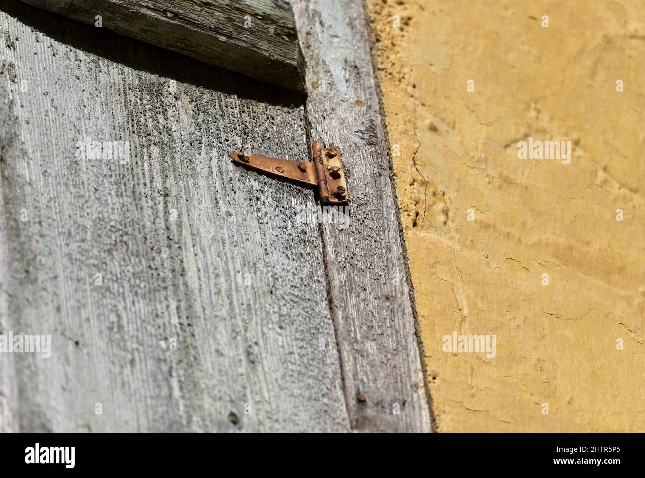 Old weathered wooden window shutters with a rusty hinge against a faded ...