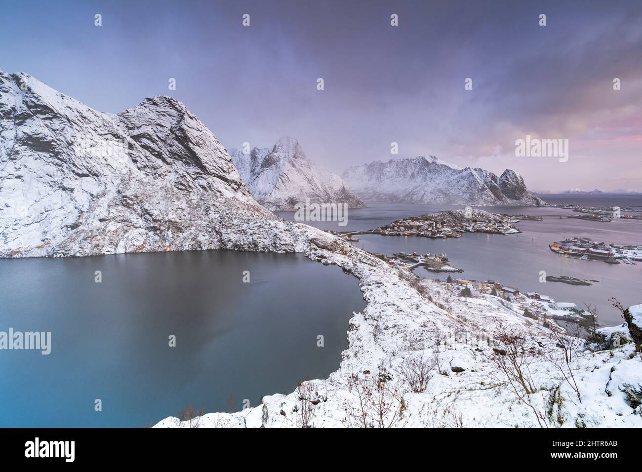 Mist at dawn over lake Reinevatnet, Reine Bay and snowcapped Olstind mountain peak, Nordland, Lofoten Islands, Norway Stock Photo