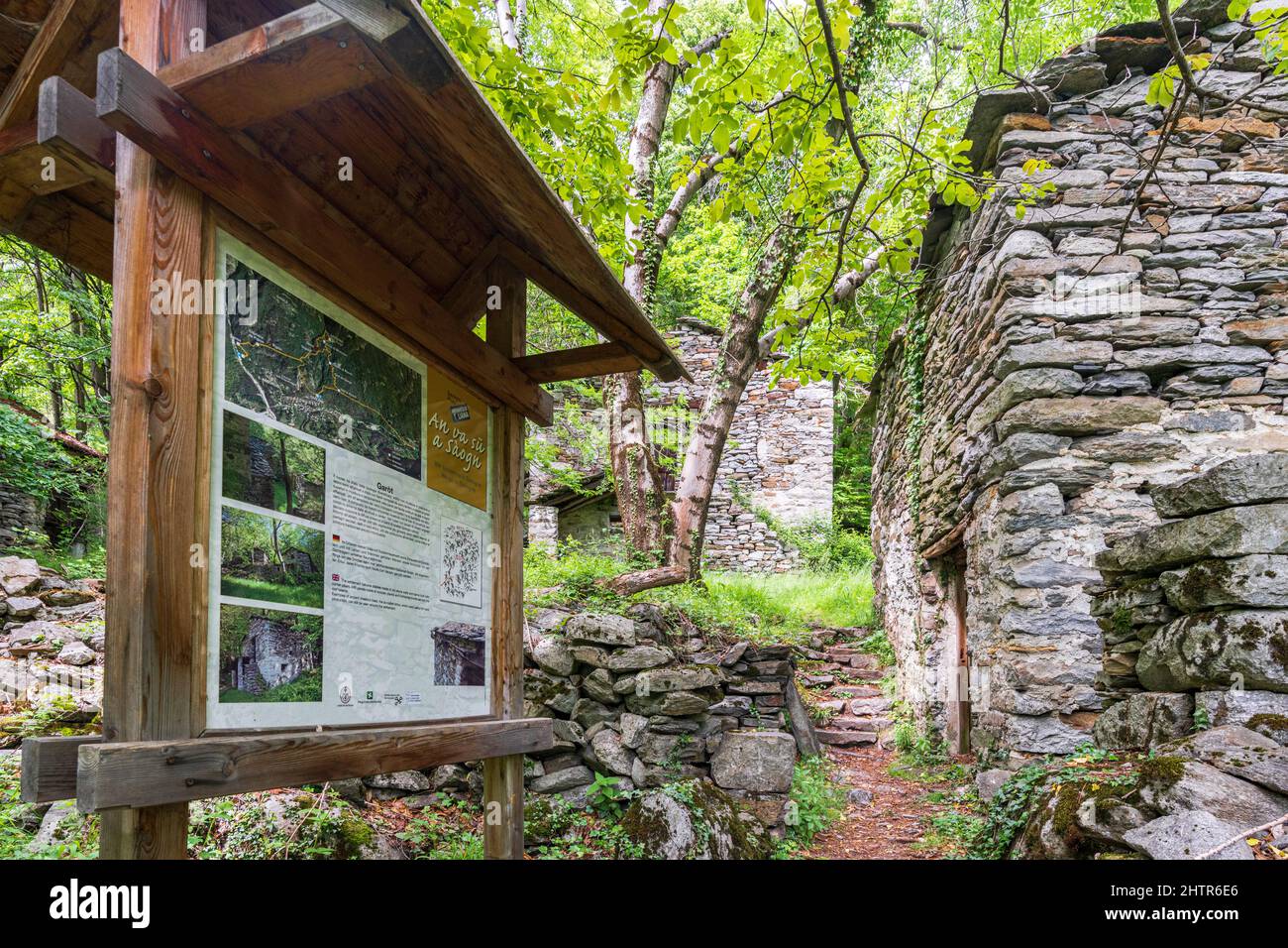 Stone huts and hiking signage along the alpine path of Crana Savogno, Piuro, Valchiavenna, Valtellina, Lombardy, Italy Stock Photo
