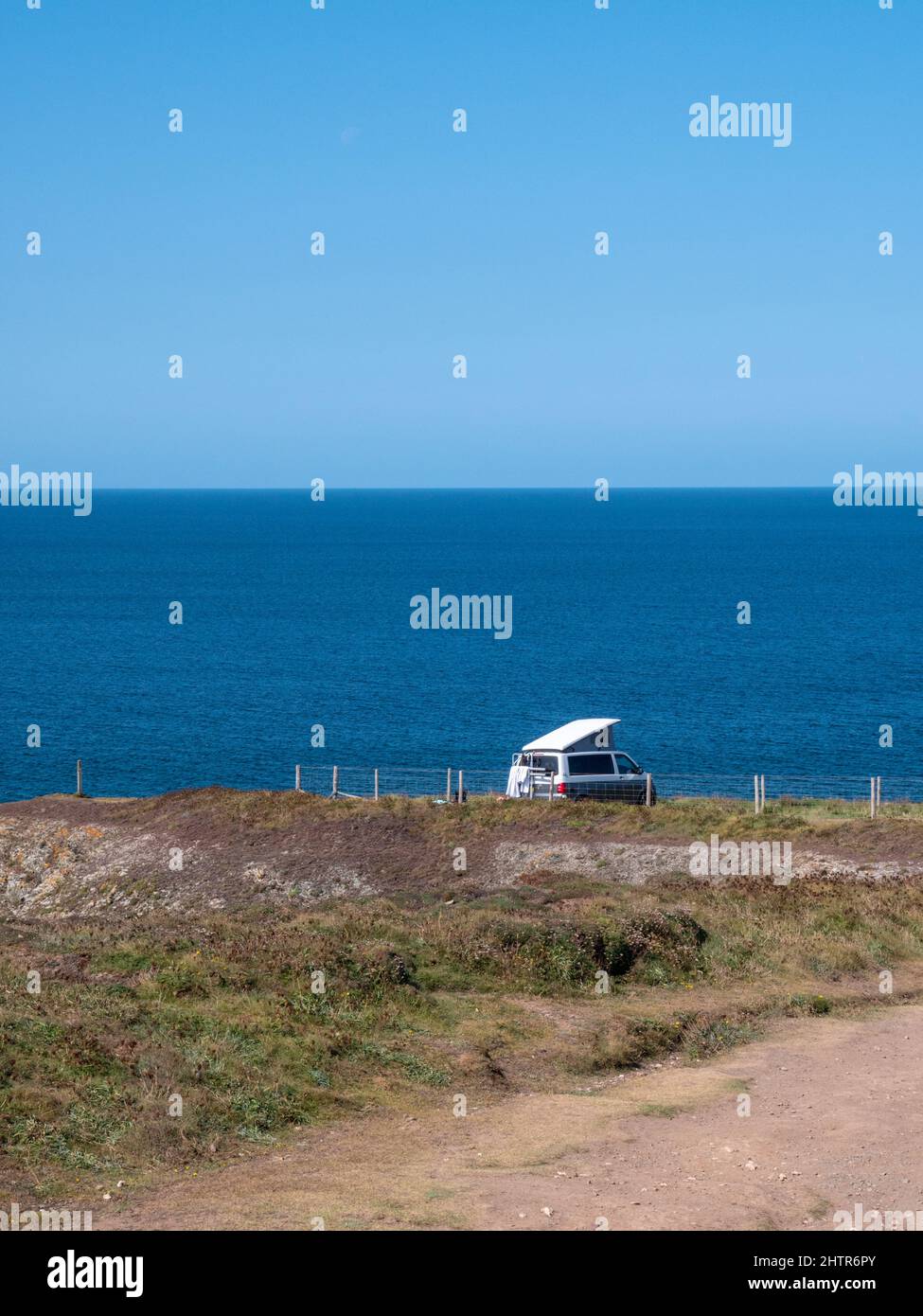 A campervan parked on a cliff top site in Porthcothan Bay Cornwall UK with a sea view in summer. Stock Photo
