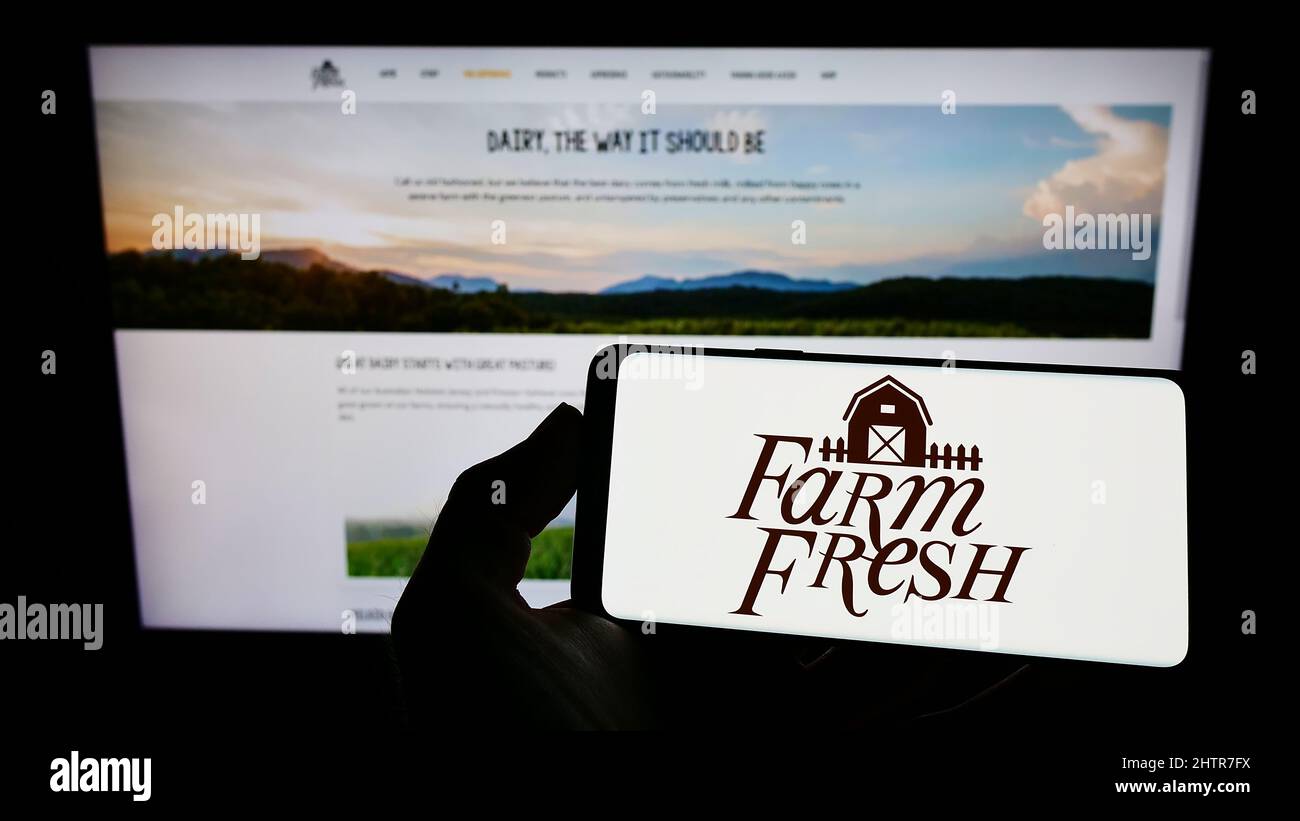 Person holding cellphone with logo of Malaysian dairy company Farm Fresh Berhad on screen in