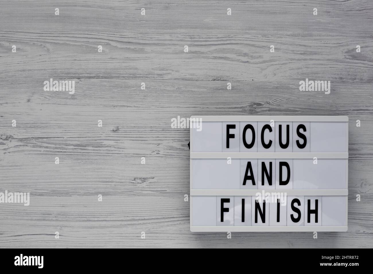 'Focus and Finish' on a lightbox on a white wooden surface, top view. Flat lay, overhead, from above. Stock Photo