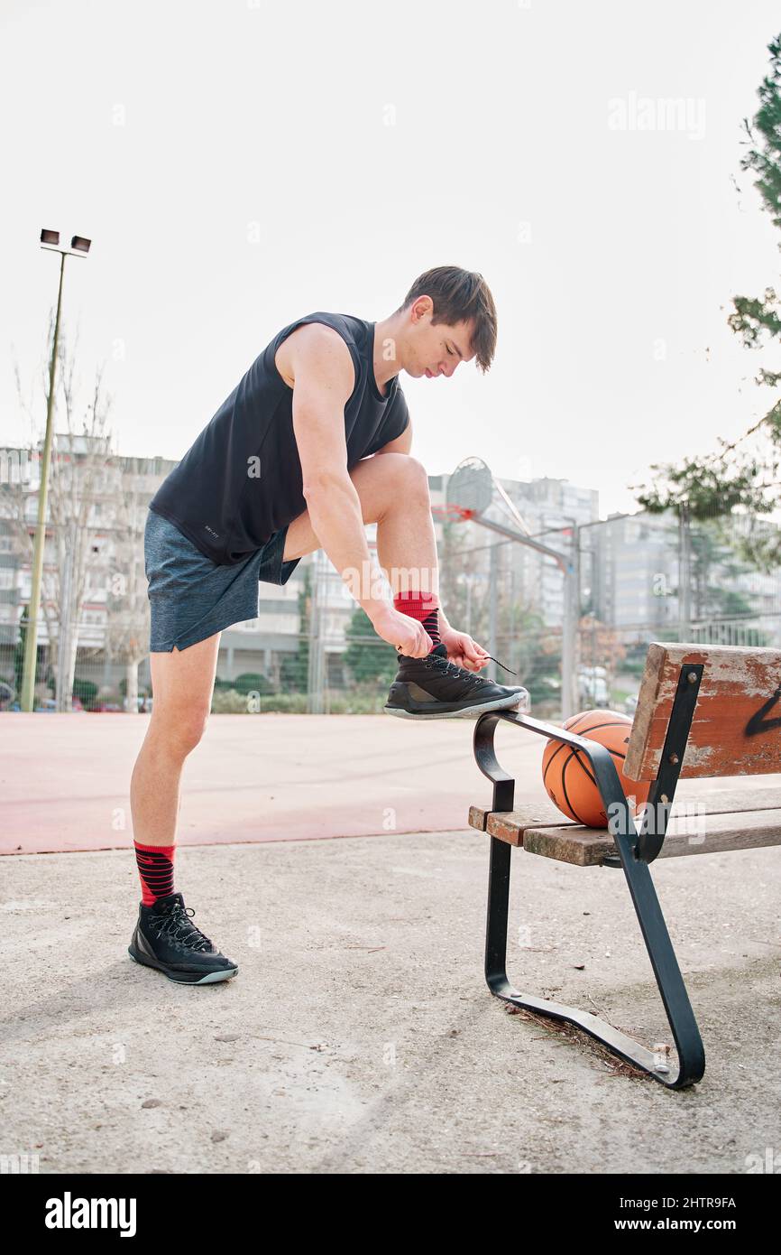 basketball player tying shoelaces on a court Stock Photo Alamy