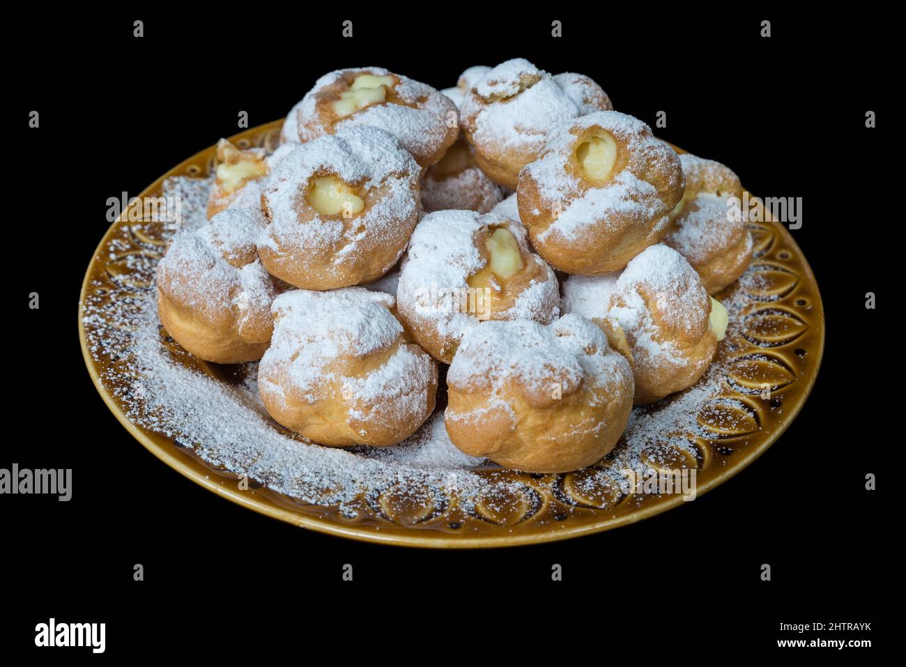 Cream puffs stuffed with custard isolated on black background. Selective focus, view from above Stock Photo