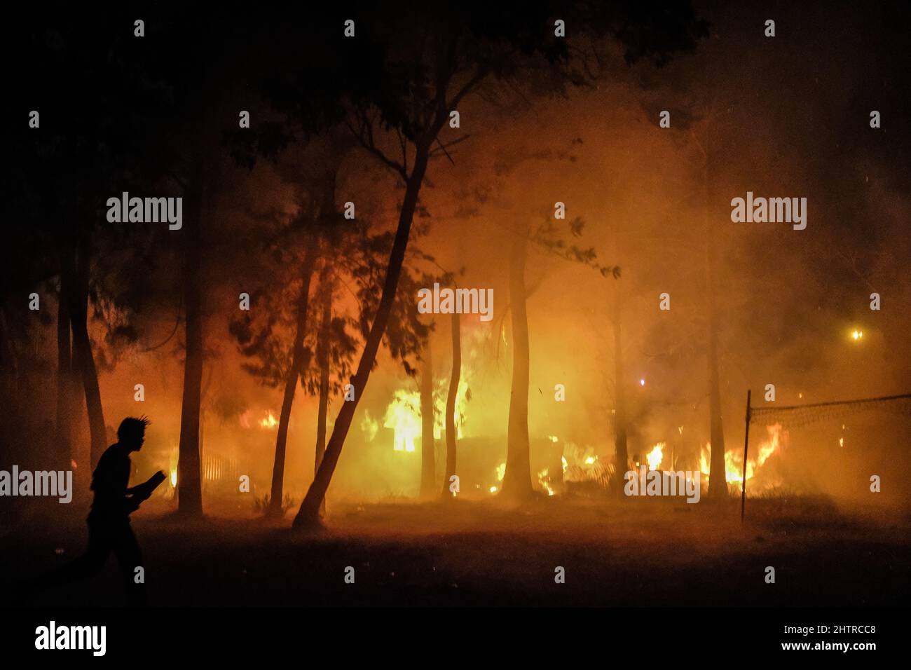A man runs past a burning forest to help homes during a fire outbreak in Kibera Slums, Nairobi. On March 1st, 2022. Residents of Kibera Slums experien Stock Photo