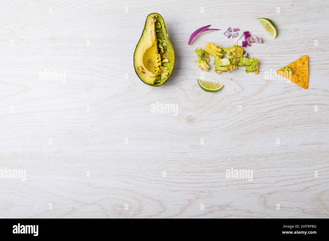Overhead view of halved avocado and ingredients on table with empty space Stock Photo