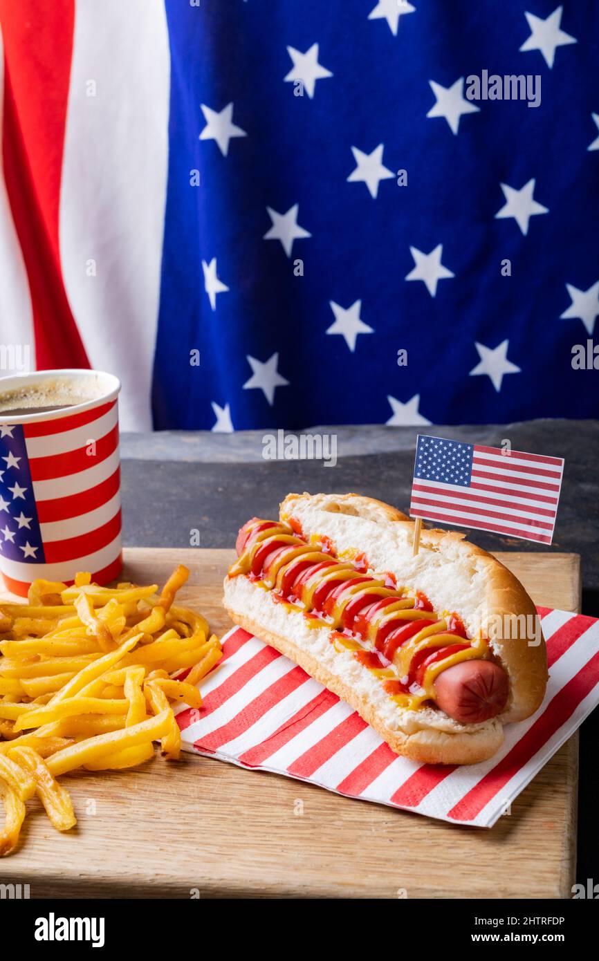 Close-up of hot dog meal served on serving board against american flag at table Stock Photo