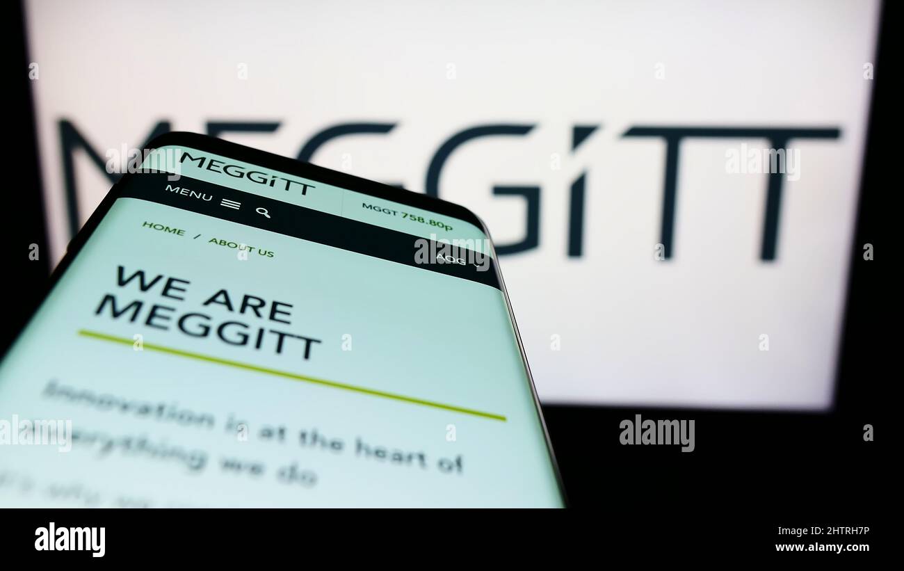 Mobile phone with website of British aerospace company Meggitt plc on screen in front of business logo. Focus on top-left of phone display. Stock Photo
