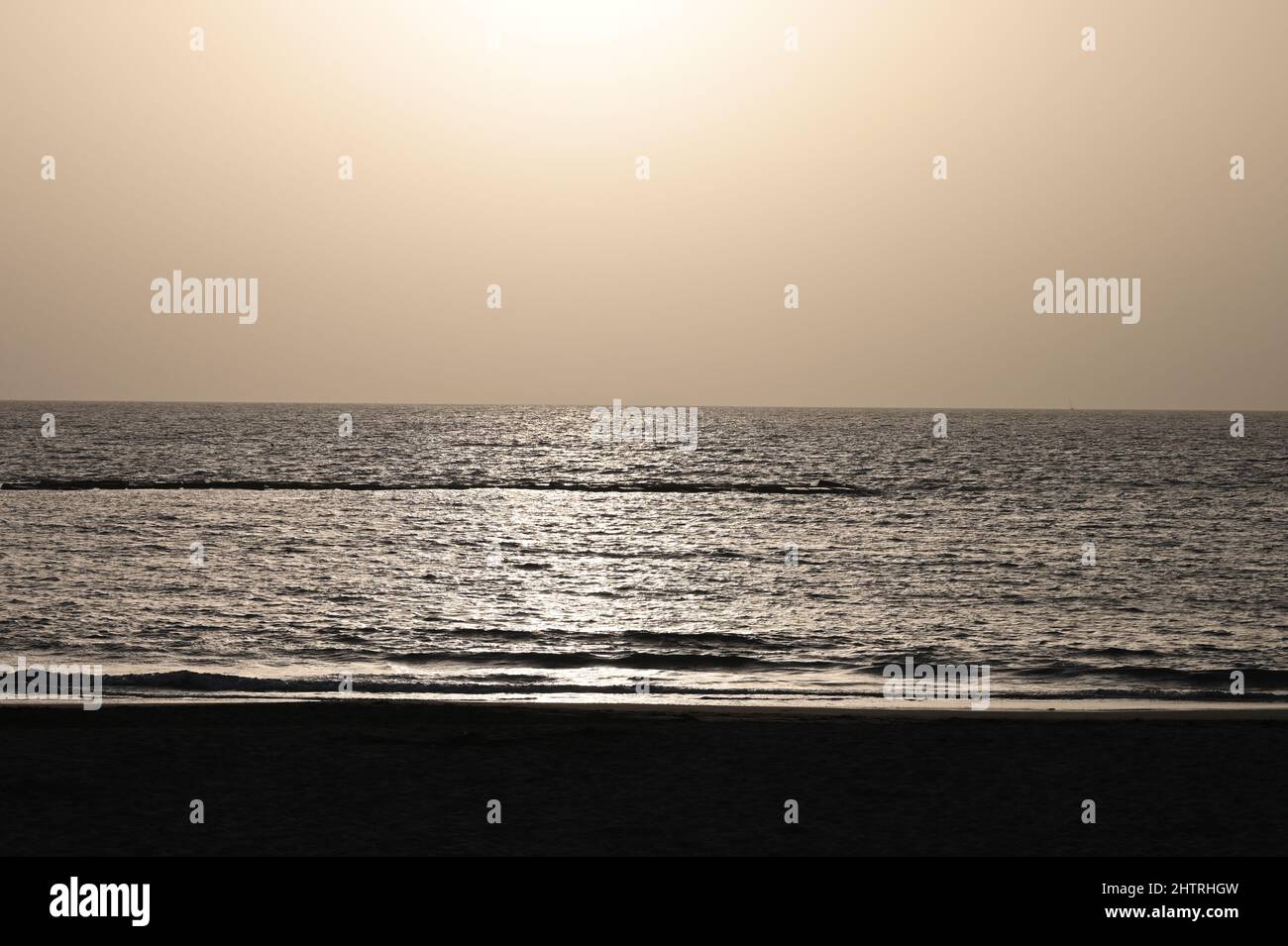 A view of the sunset over the Atlantic Ocean, in Costa Adeje, Tenerife, Spain, with the glistening beams of the sun reflecting on the ocean Stock Photo