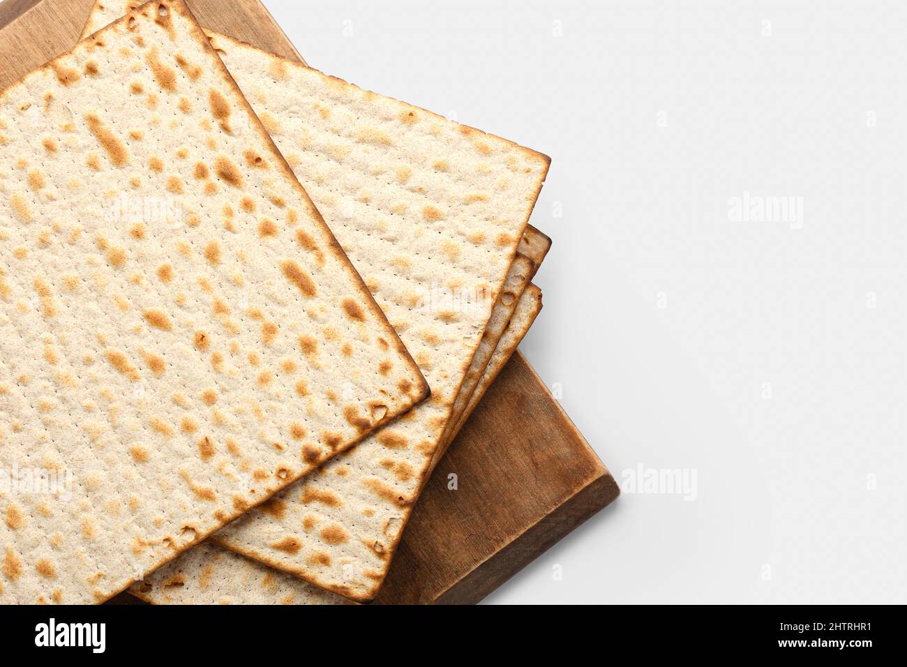 Wooden board with Jewish flatbread matza for Passover on white
