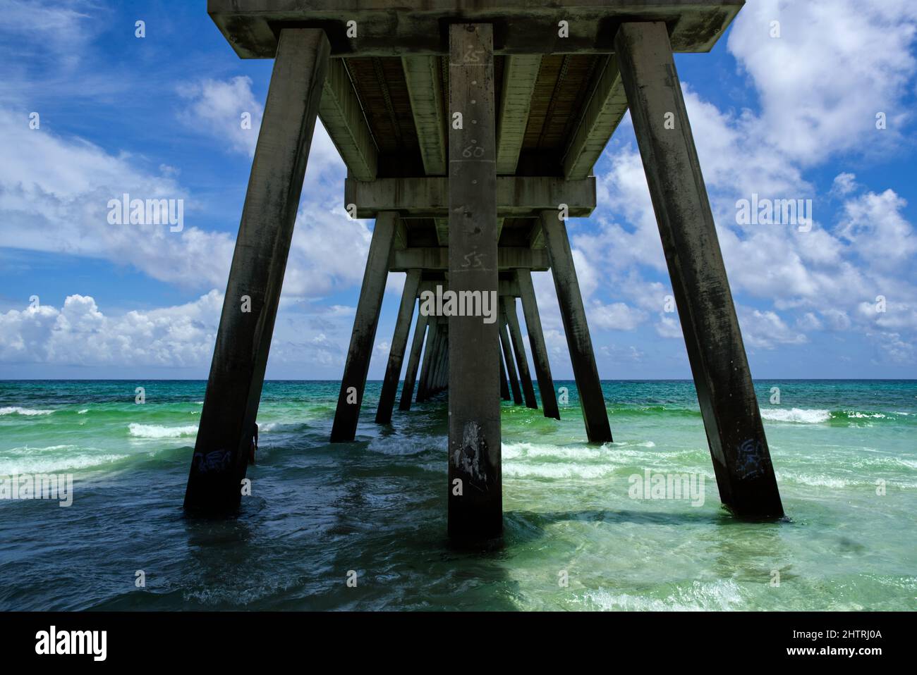 Low angle shot of the bottom of a pier with sea water ans the sky in the background Stock Photo