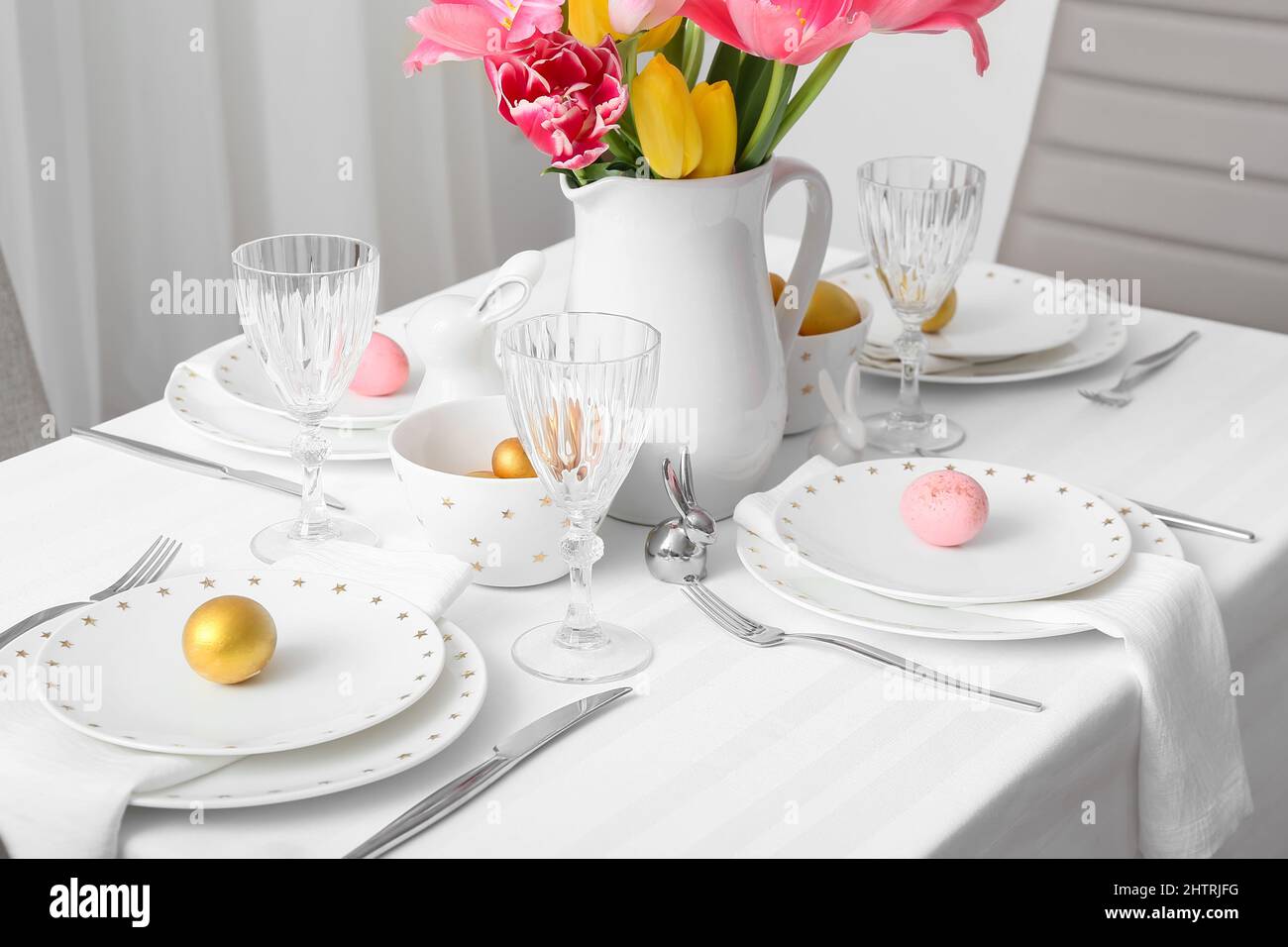 Beautiful table setting with Easter eggs and tulips in room Stock Photo