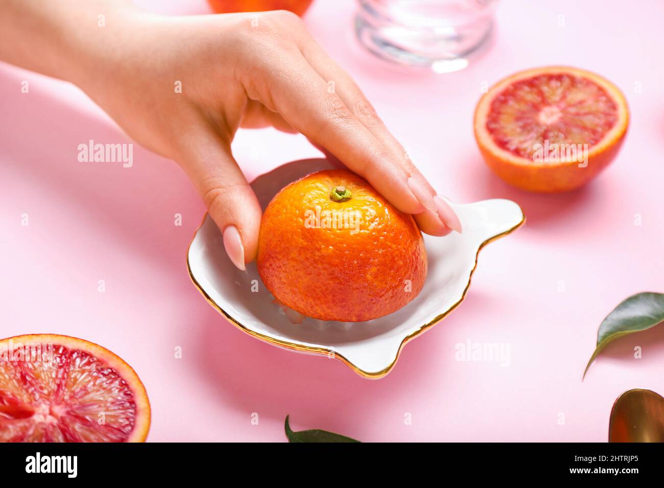 Woman squeezing fresh grapefruit on pink background Stock Photo