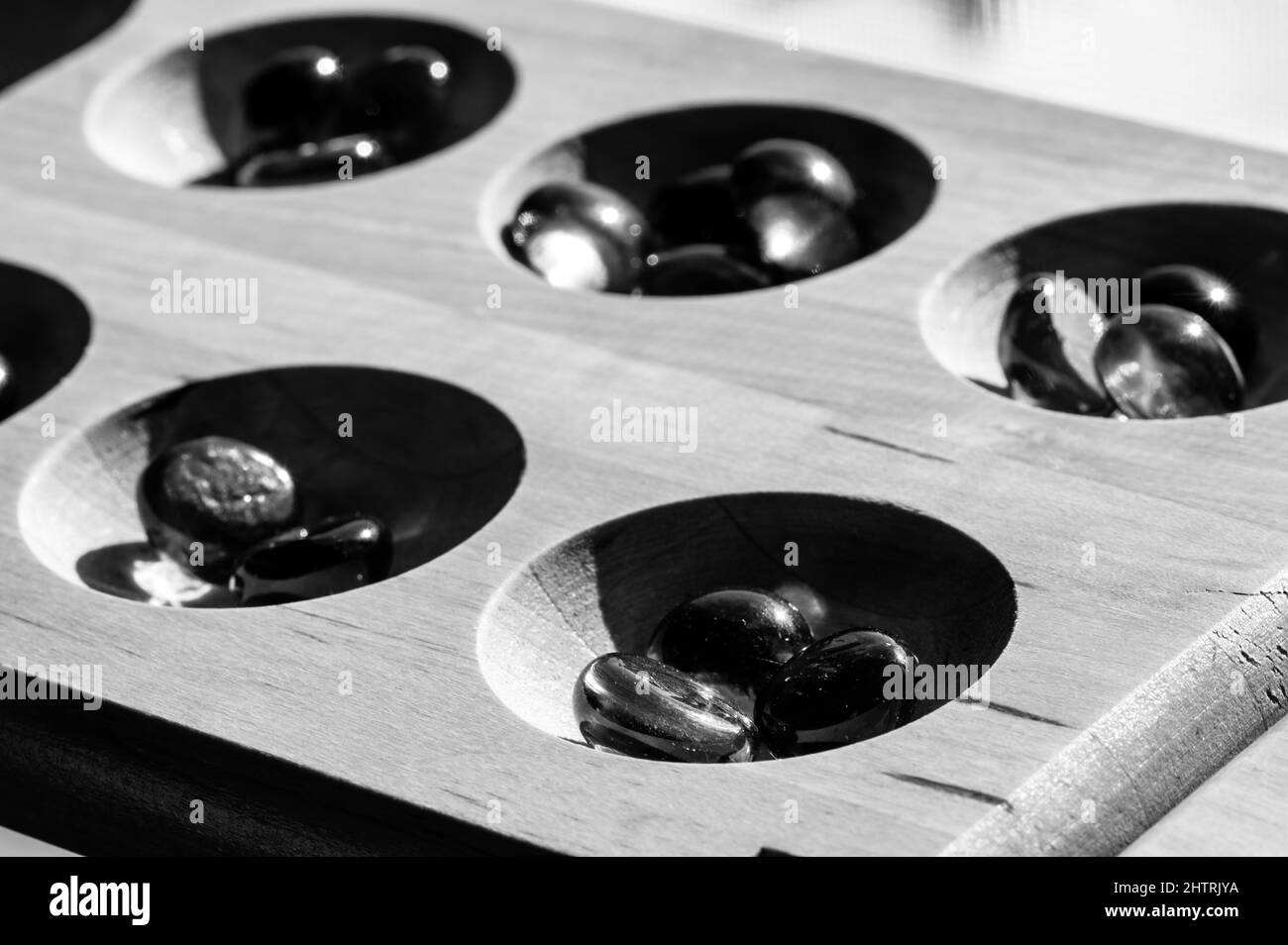 Selective focus on glass beads on a wooden mancala board Stock Photo