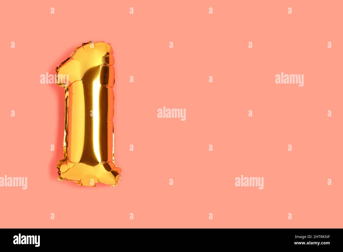 Number 1 golden balloon with copyspace. One year anniversary celebration concept on a coral colored background. Stock Photo