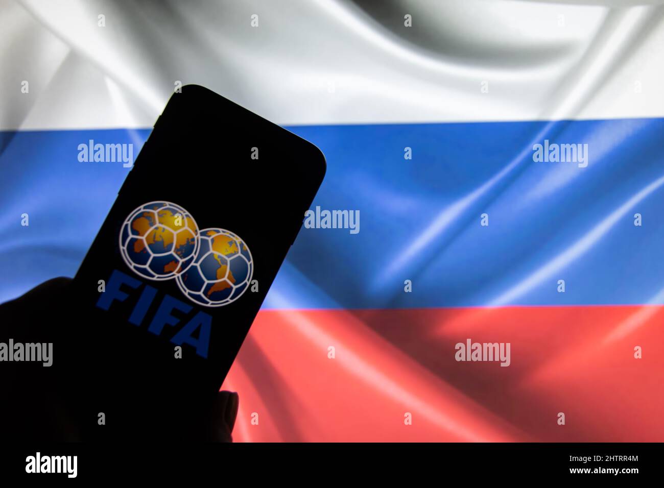 Rheinbach, Germany  4 March 2022,  The 'FIFA' brand logo on a smartphone display in front of a Russian flag (focus on the brand logo) Stock Photo