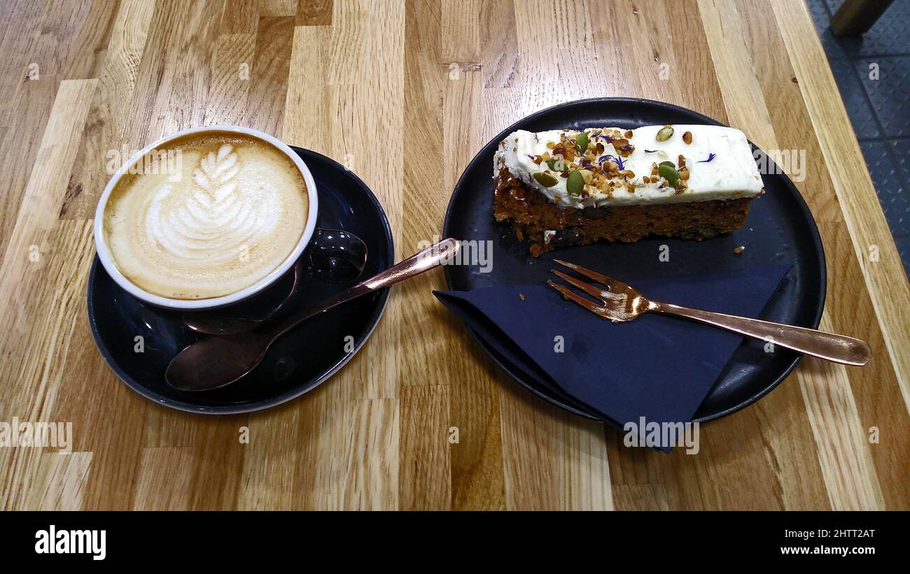 WARRINGTON. CHESHIRE. ENGLAND. 19-02-22. The new market hall, a latte coffee served with a portion of vegan carrot cake. Stock Photo