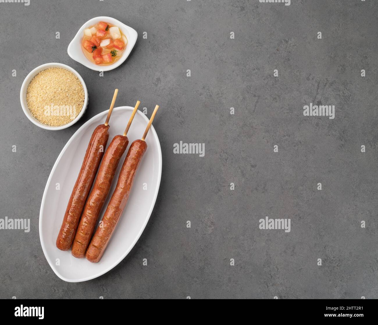 Pork sausage skewers with farofa, vinaigrette and copy space over stone background Stock Photo