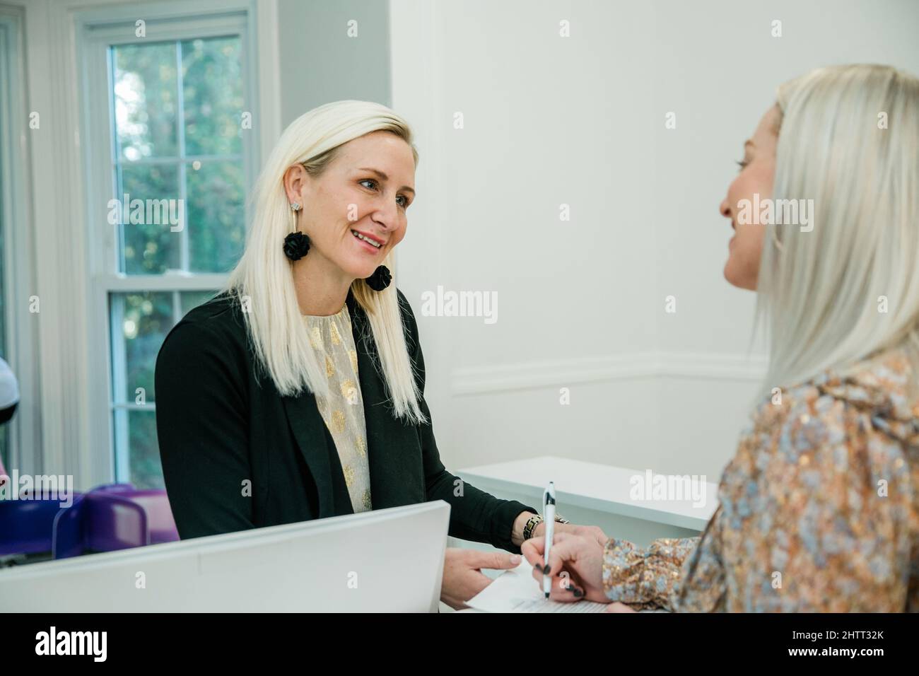 A small business owner checking in a guest client at a wellness spa Stock Photo