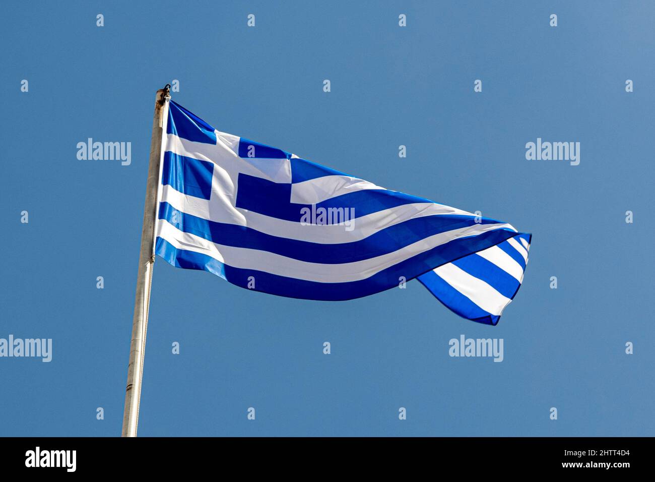 Flag of Greece waving in blue sky Stock Photo