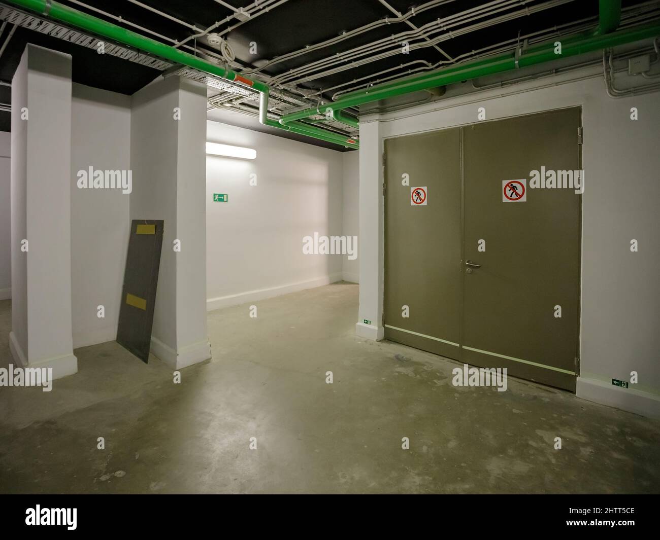 Entrance to the technical room of a modern building. Technical room, corridor. The walls and the ceiling mounted thermally insulated pipelines. Stock Photo