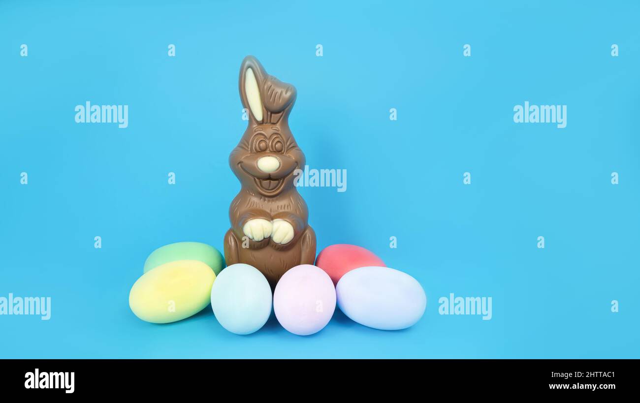 Easter Chocolate Bunny and eggs are plain, multi-colored on a blue background  Stock Photo