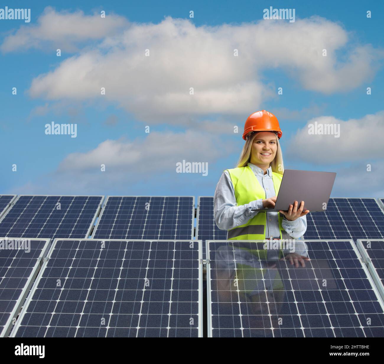 Young female engineer working on a laptop computer behind solar panels Stock Photo