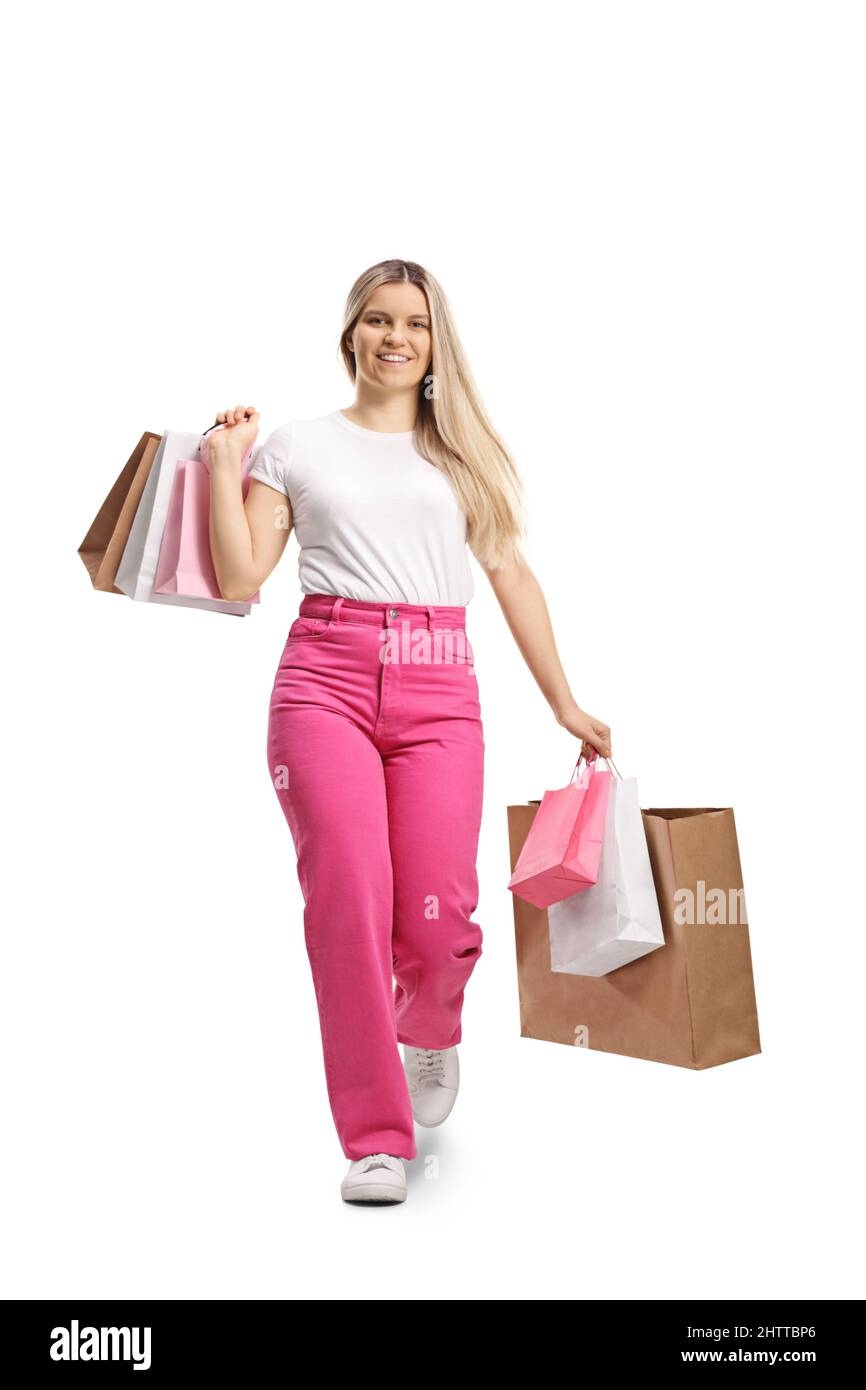 Full length portrait of a young casual female in pink jeans walking with shopping bags isolated on white background Stock Photo