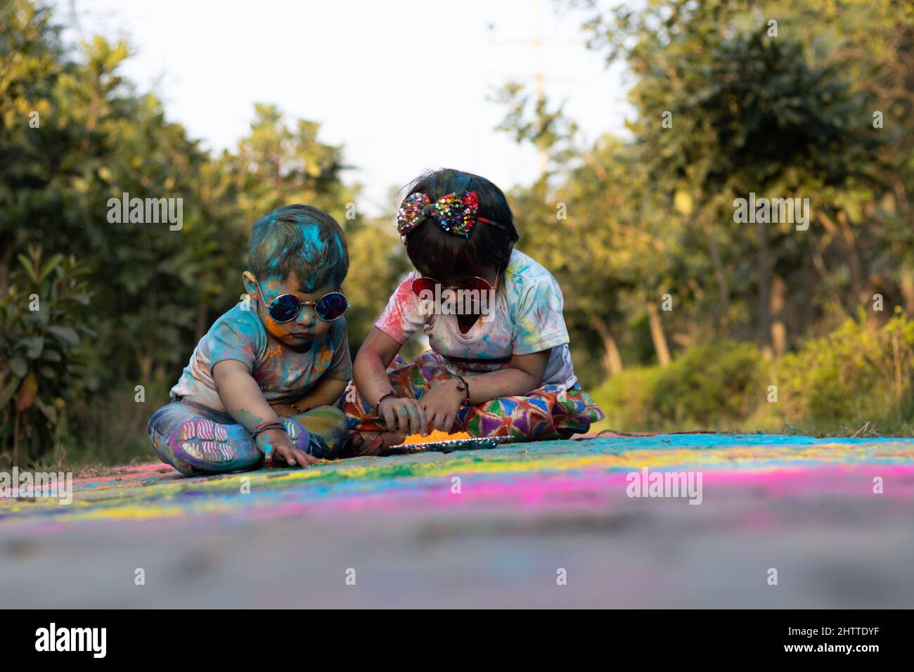 Happy Asian Indian Kids Boy And Girl Enjoying The Festival Of Colors With Holi Color Powder Called Gulal Or Rang Stock Photo