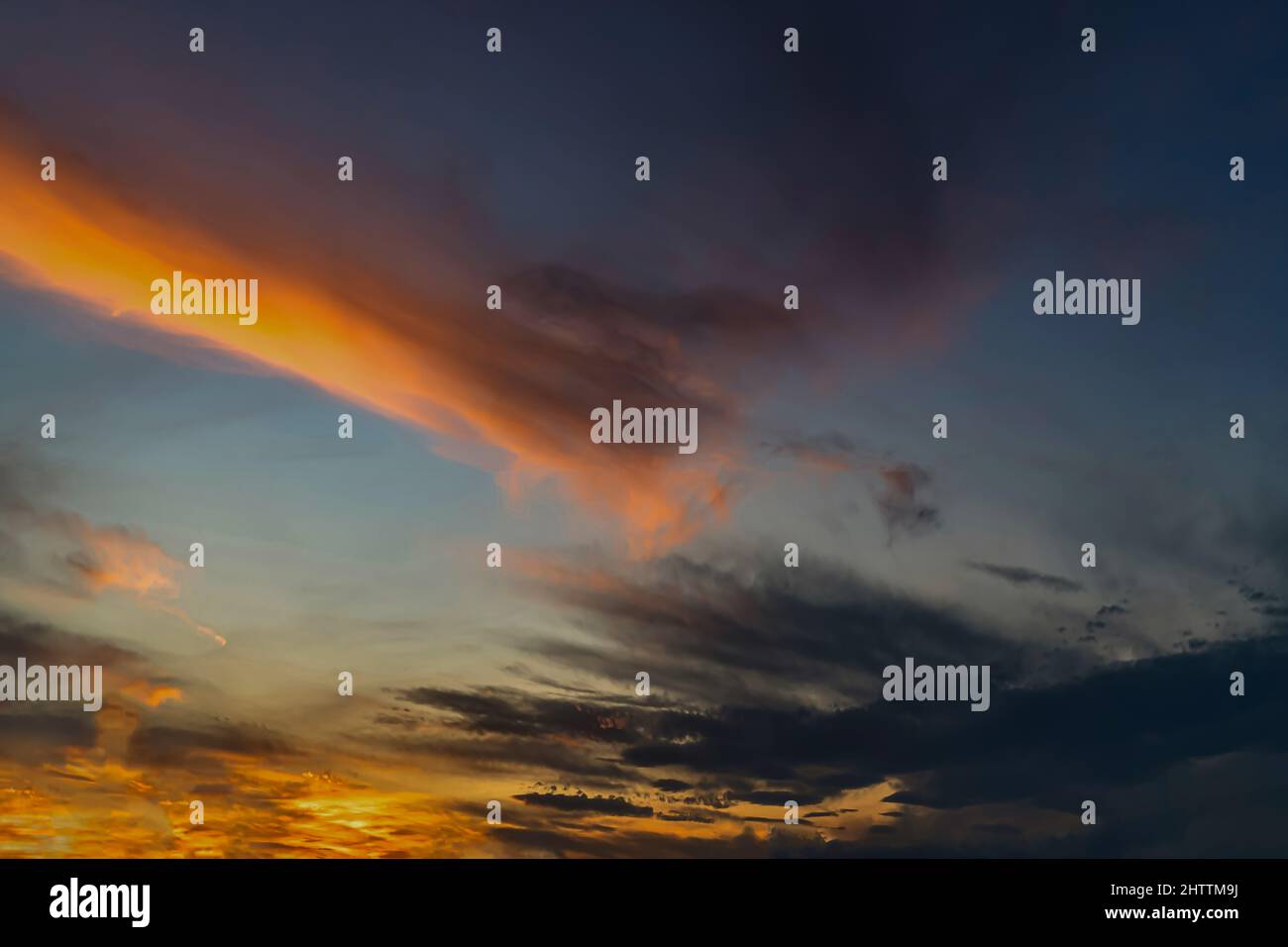 Panorama of dramatic colorful sunset with dark and bright clouds. Stock Photo