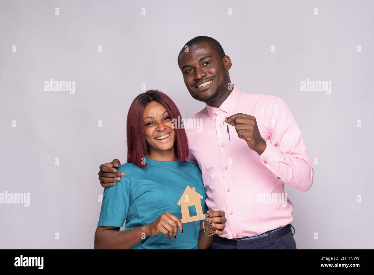Happy African couple holding a smal wooden house and the keys together ...