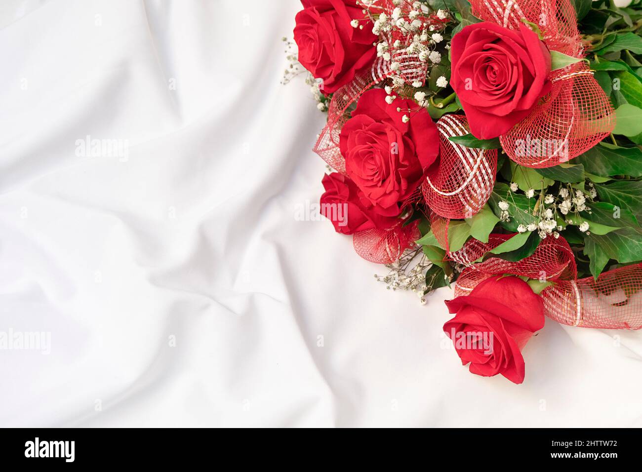 Top view of beautiful bouquet on white bed sheet. Romantic surprise background, copy space Stock Photo