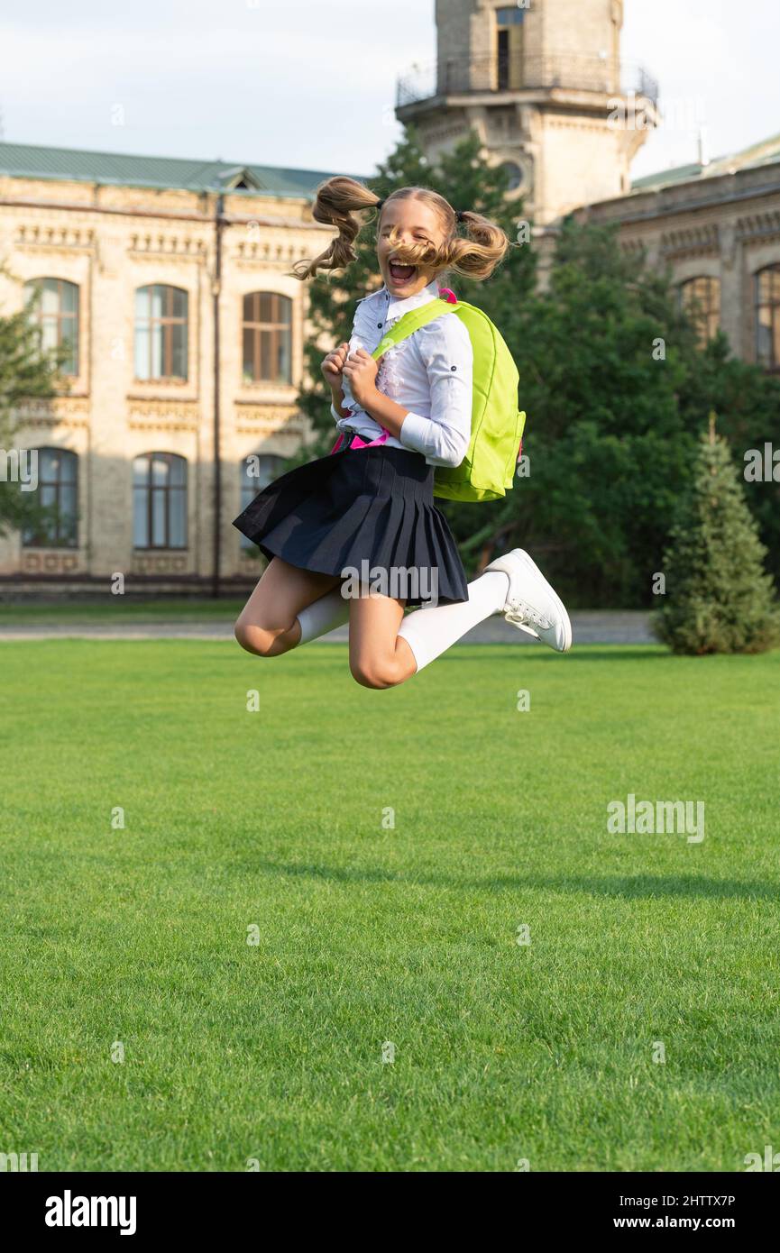 Happy energetic girl in uniform with school bag jumping for joy, back ...