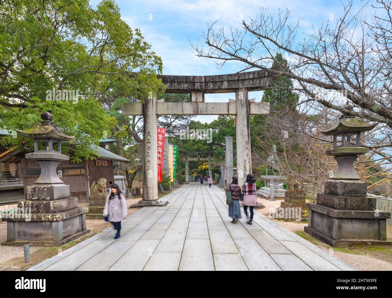 kyushu, japan - december 08 2021: Japanese tourists strolling along the sacred sandō path of Miyajidake Shrine surrounded by stone lanterns and komain Stock Photo