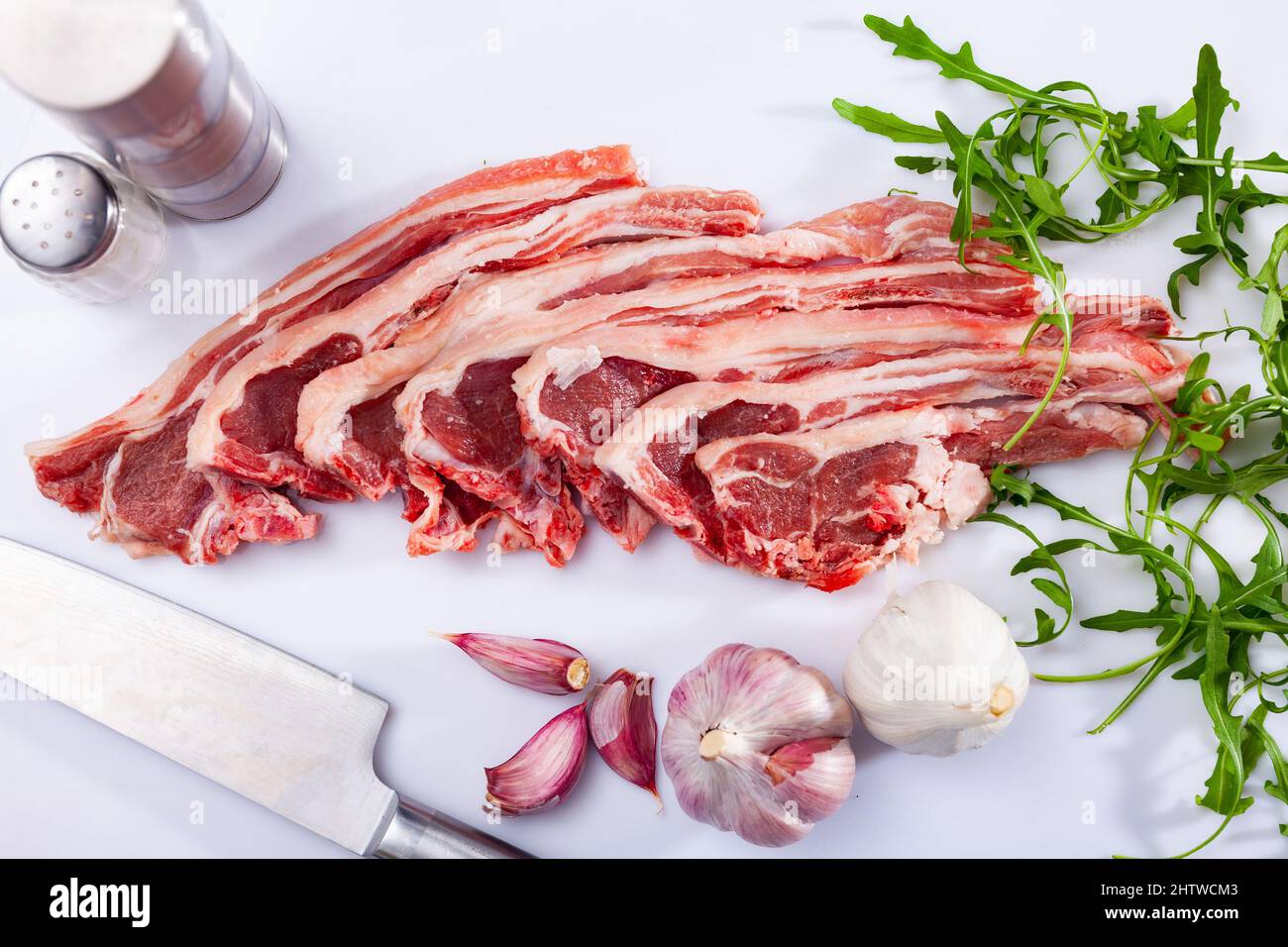 Raw lamb chops on kitchen table with garlic, arugula, spices Stock Photo
