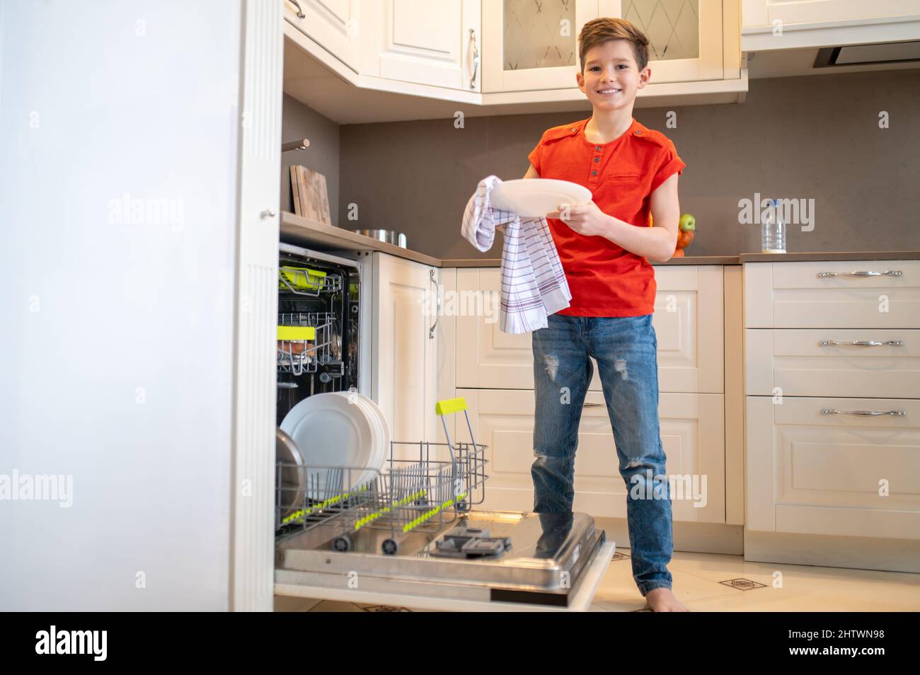 Teen drying a washed plate with a kitchen towel Stock Photo