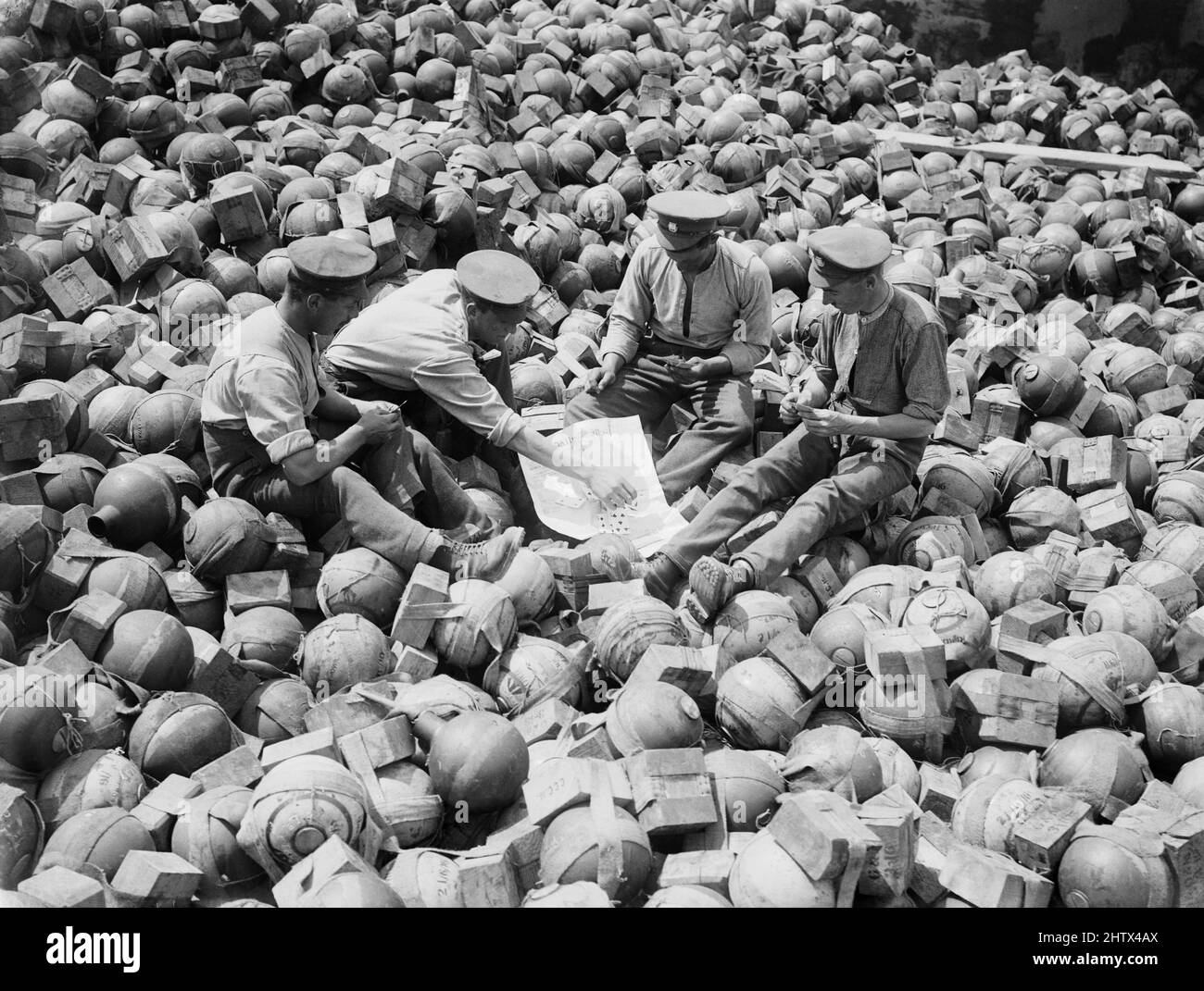 Men of the Royal Army Ordnance Corps playing cards on a dump of 2 inch mortar bombs ('Toffee Apples') at Acheux, July 1916 during The Battle of the Somme Stock Photo