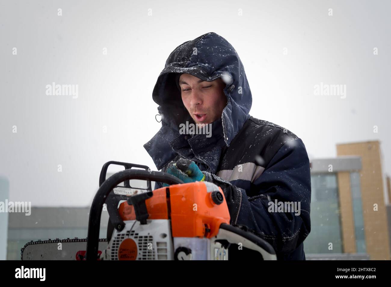 The worker checks the condition of the chainsaw before work Stock Photo