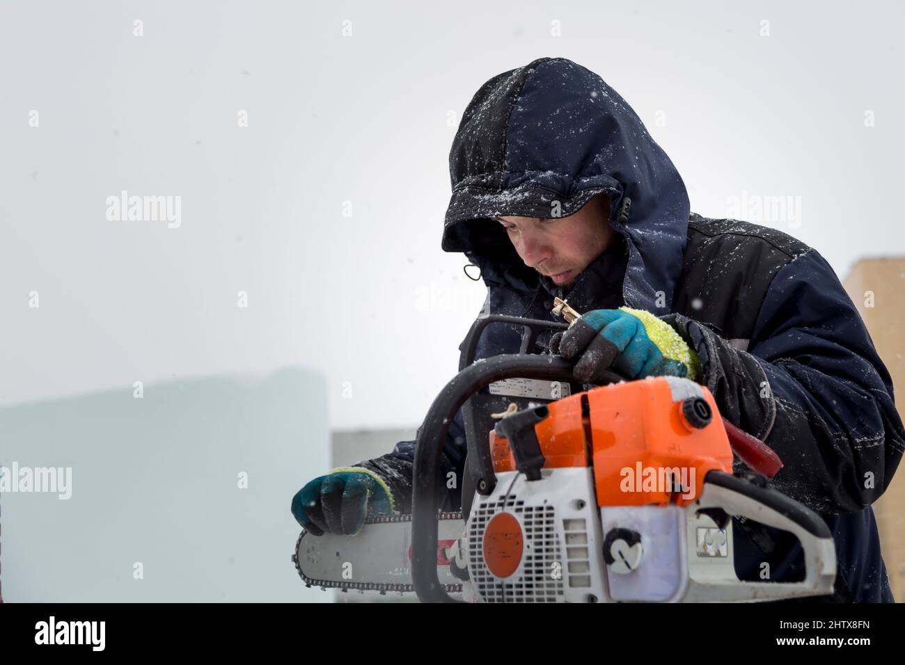 The worker checks the condition of the chainsaw before work Stock Photo