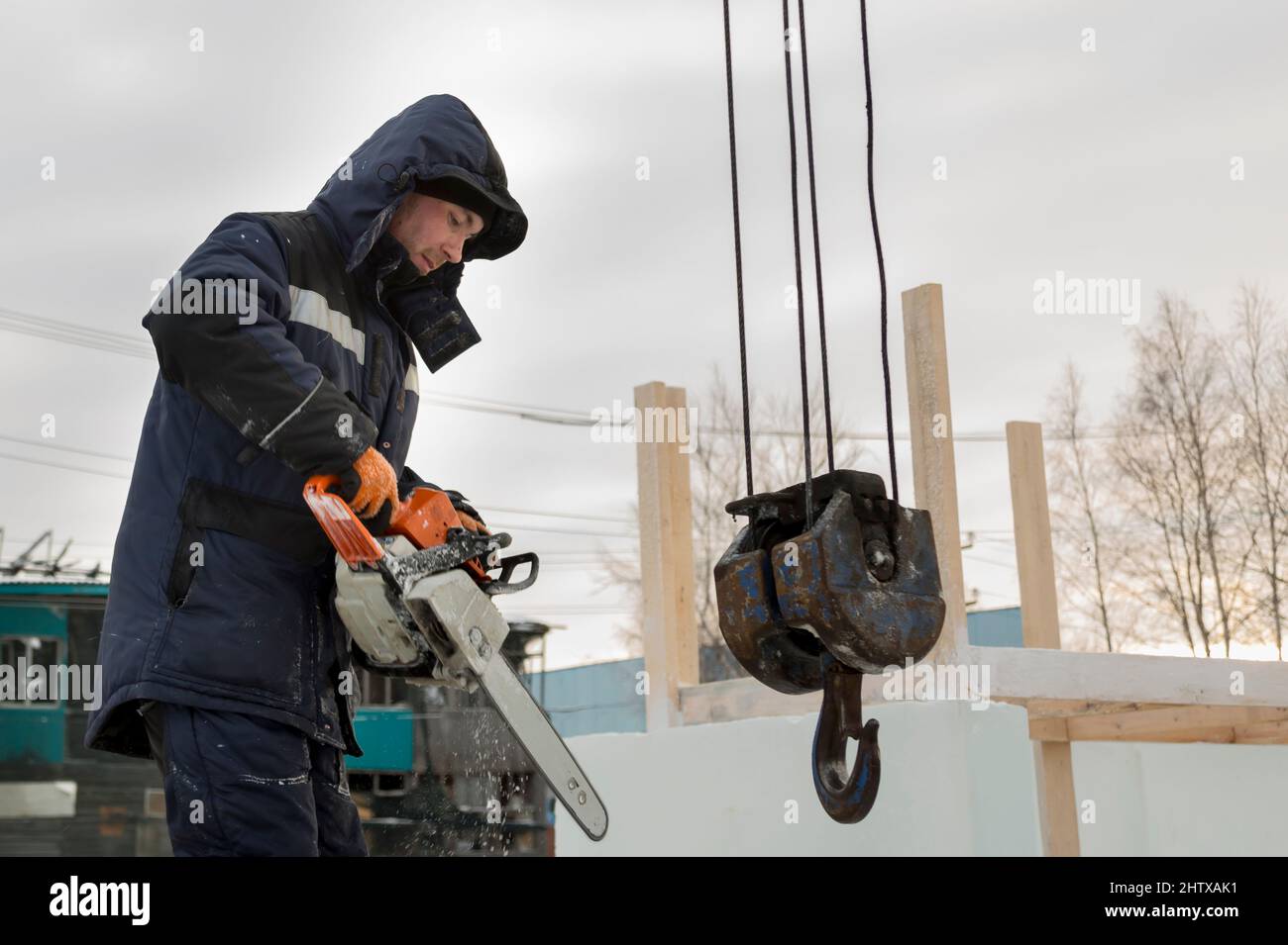 Worker with a chainsaw in hand at the assembly site Stock Photo
