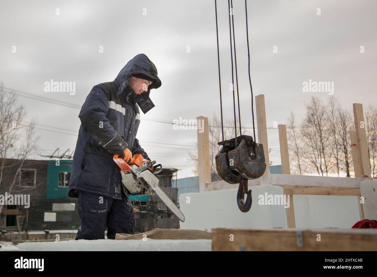 Worker with a chainsaw in hand at the assembly site Stock Photo