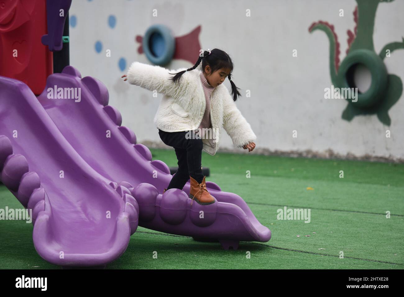 A little girl is playing on a slide in a kindergarten.The National Bureau of Statistics of China released the Statistical Communique on the 2021 National Economic and Social Development. According to the communique, China's population at the end of 2021 was 1,412.6 million, an increase of 480,000 over the previous year, including 914.25 million permanent urban residents. There were 10.62 million births, with a birth rate of 7.52 per thousand. 10.14 million people died, with a mortality rate of 7.18 per thousand. The natural growth rate is 0.34%. Stock Photo