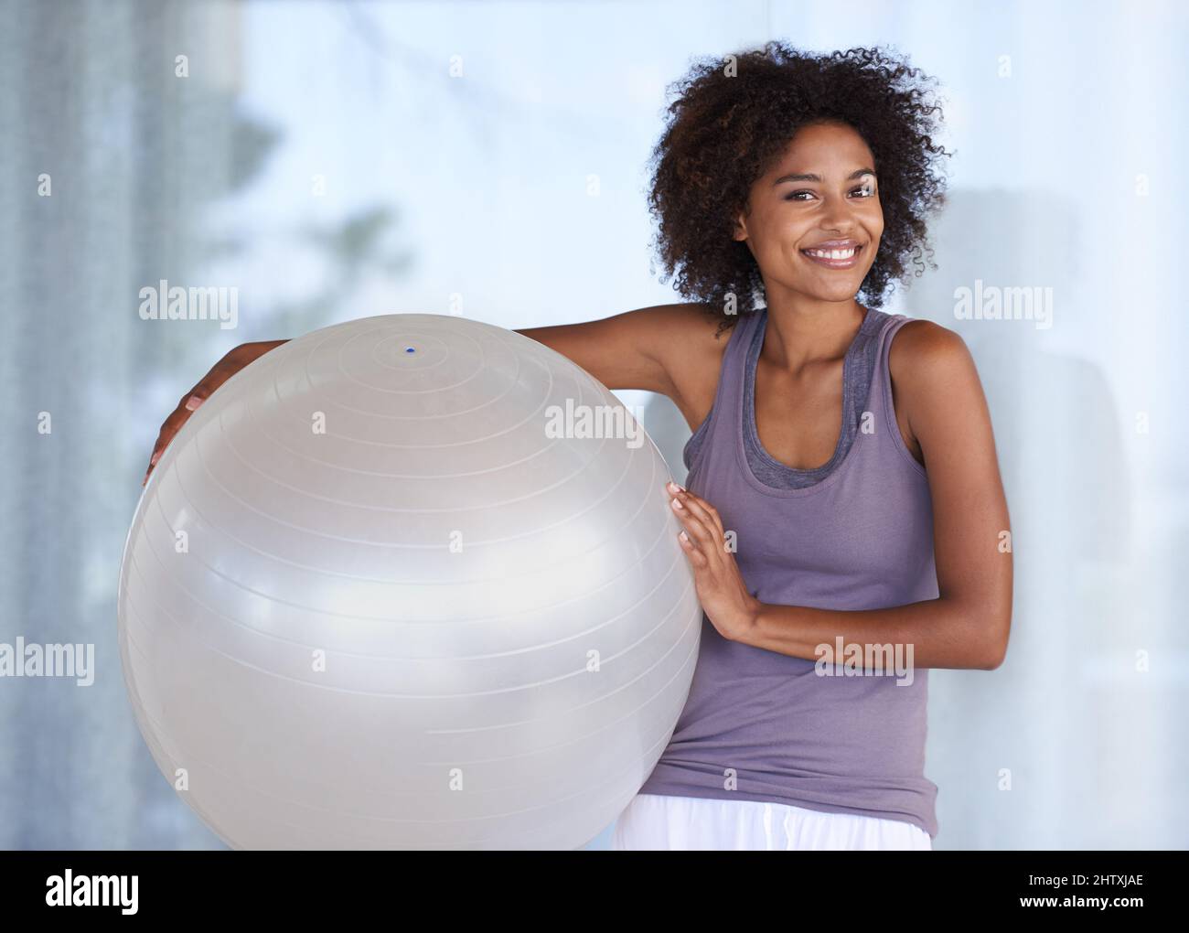 This ball is my secret to fitness. an attractive young woman working out with an exercise ball by a swimming pool Stock Photo Alamy