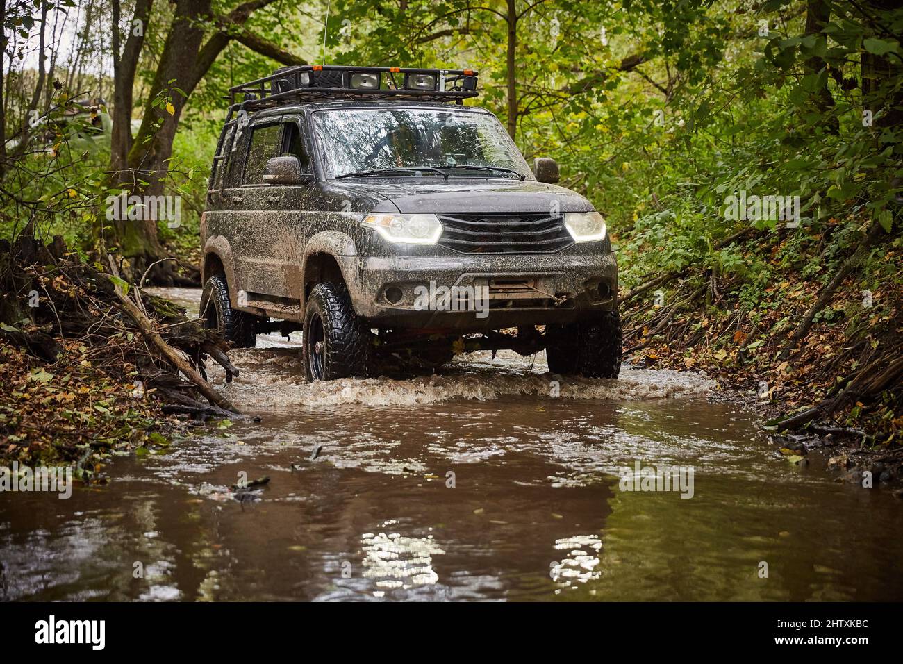 Moscow region, Russia - 28.09.2018. Traveling off-road on a black UAZ Patriot truck. The car is driving along a stream in the forest Stock Photo