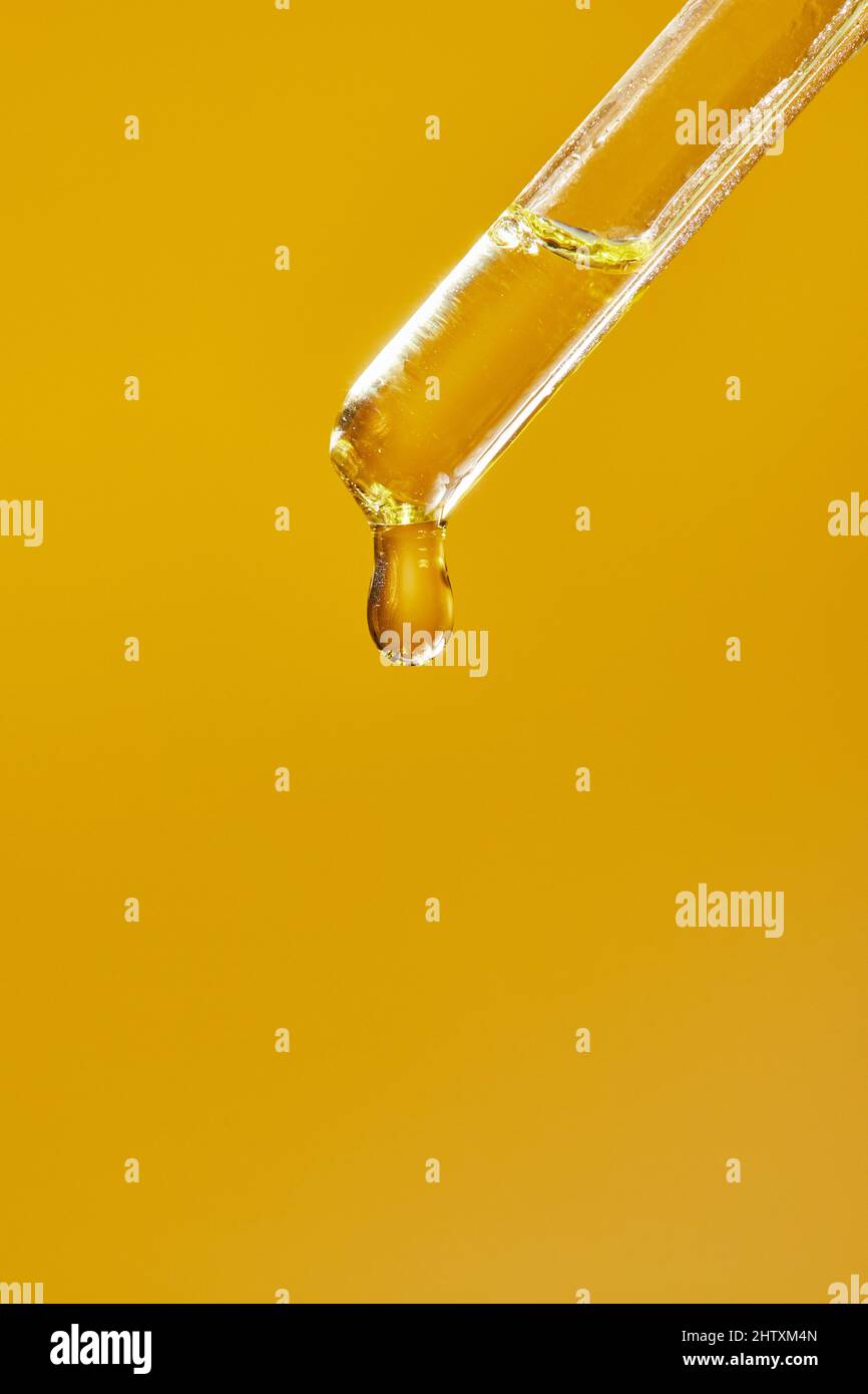 A drop of cosmetic aromatic oil drips from the pipette. Front view