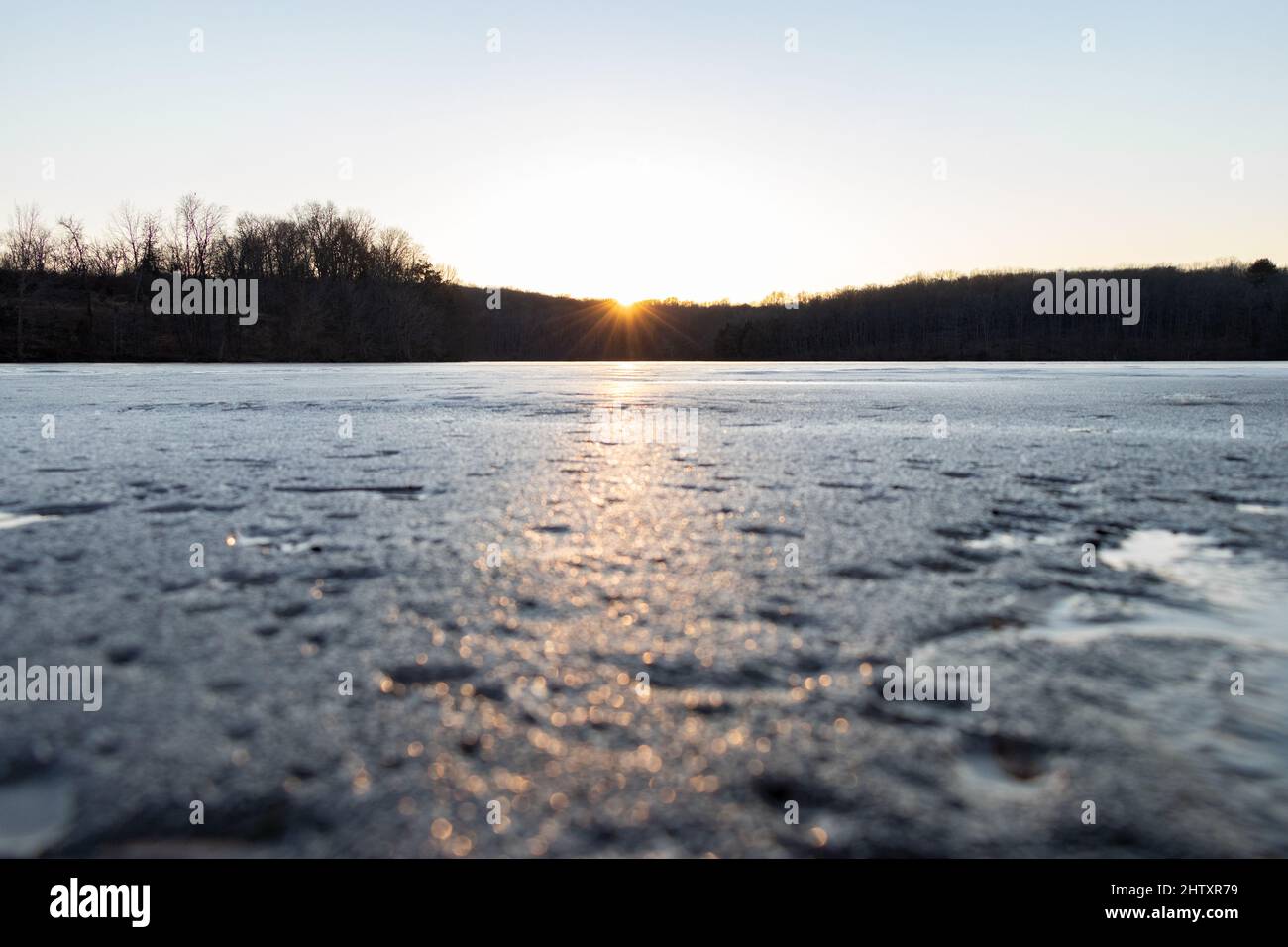 Beautiful sunset over a frozen lake with trees in a background on a ...