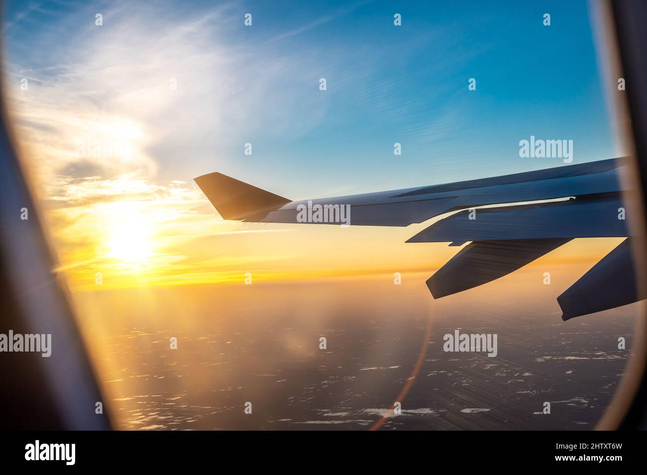 airplane wing at sunset. travel, air travel. Flight during dawn, a beautiful view in window of an airplane with bright sky. Travel, tourism, vacations Stock Photo