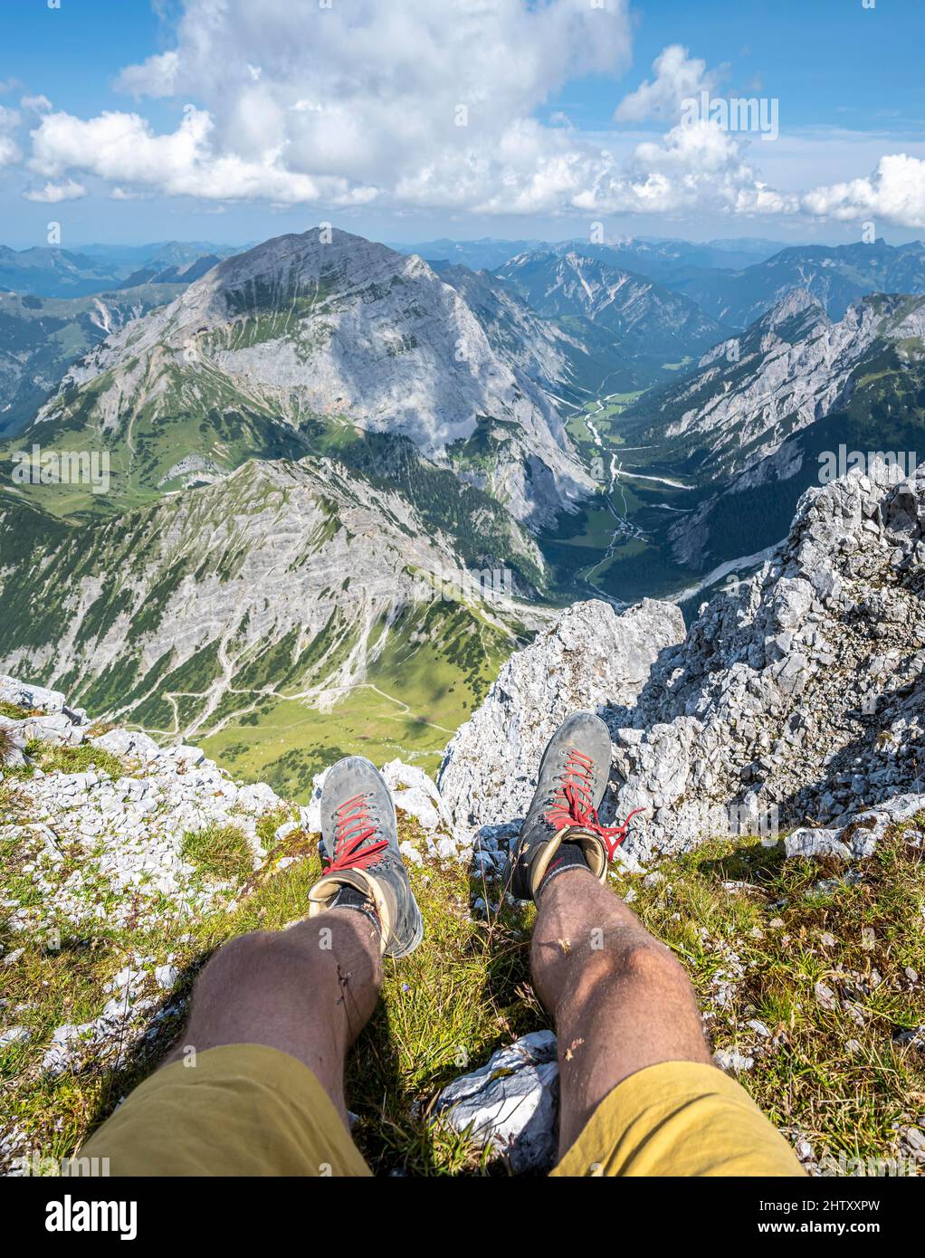 Mountain landscape, hiker lets his legs dangle, hiking boots and view from the Lamsenspitze to mountains and the Gramaital, Karwendel Mountains Stock Photo