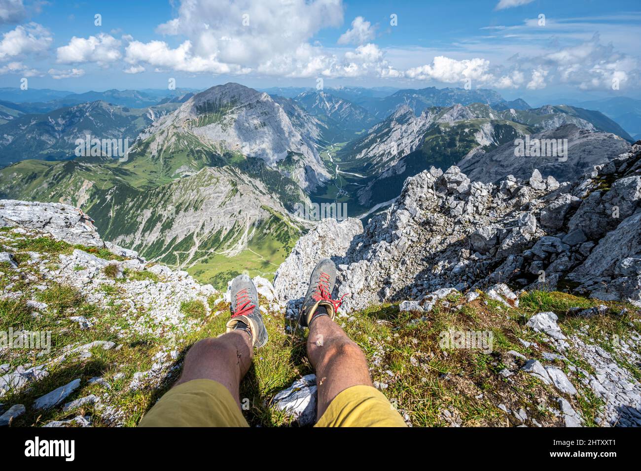 Mountain landscape, hiker lets his legs dangle, hiking boots and view from the Lamsenspitze to mountains and the Gramaital, Karwendel Mountains Stock Photo